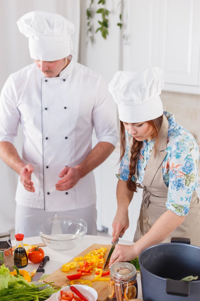Two chefs in a kitchen chopping vegetables and preparing a meal.